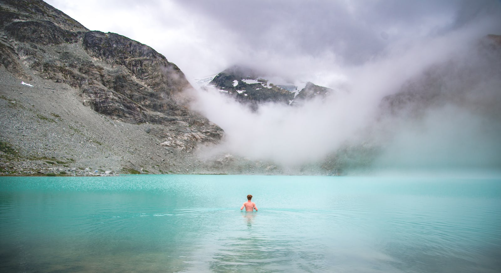 Man swimming in a mountain lake in the fog